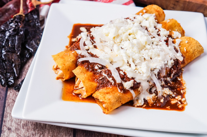 Platillo de tradicionales enchiladas de mole, con cebolla y quesillo